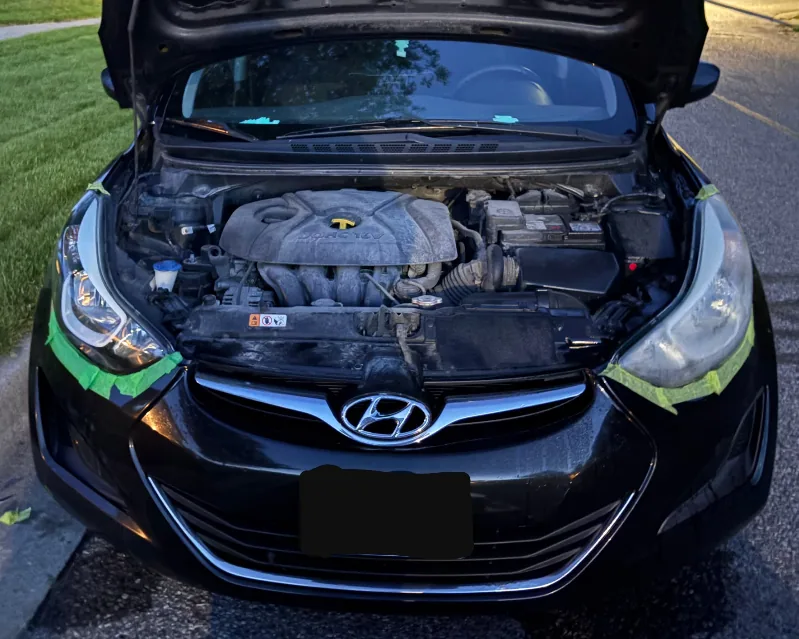 Black Hyundai with both headlights fully visible and masked during restoration